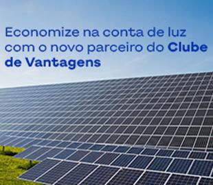 Painéis solares fotovoltaicos, com o texto Economize na conta de luz com o novo parceiro do Clube de Vantagens sobreposto no céu azul.