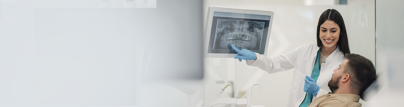 Dentista sorridente mostra radiografia odontológica a um paciente durante a consulta.