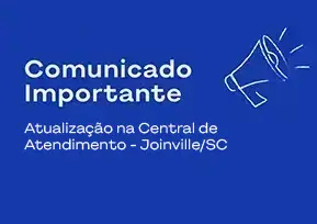 Medica sorrindo, com a caneta na mão e olhando para o notebook.